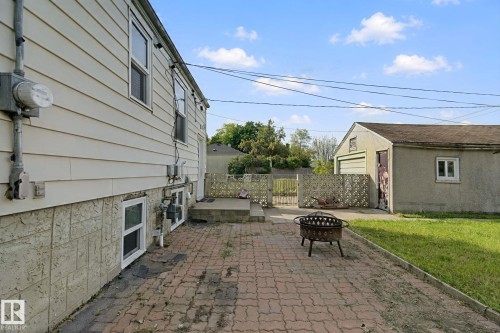 Exterior featuring horizontal siding, a block foundation, and a detached garage with a roll-up door - 11914 124 Street Nw, Edmonton, AB 