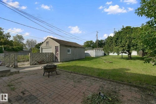 Detached two-car garage with a roll-up door, paved driveway, and established lawn - 11914 124 Street Nw, Edmonton, AB 