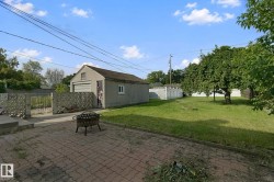 Detached two-car garage with a roll-up door, paved driveway, and established lawn - 