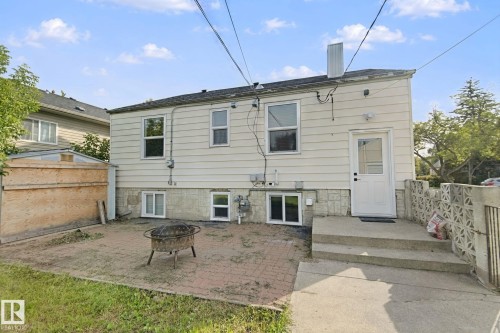 Rear exterior featuring white siding, a concrete staircase, and a concrete block retaining wall - 11914 124 Street Nw, Edmonton, AB 