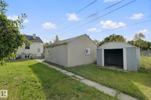 Expansive grass area featuring a detached structure, a metal storage shed, and mature foliage - 11914 124 Street Nw, Edmonton, AB 