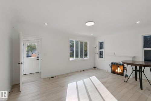 White walls, wood-finish flooring, multiple windows, recessed lighting, and a circular flush-mount ceiling light - 11914 124 Street Nw, Edmonton, AB 