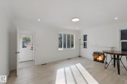 White walls, wood-finish flooring, multiple windows, recessed lighting, and a circular flush-mount ceiling light - 