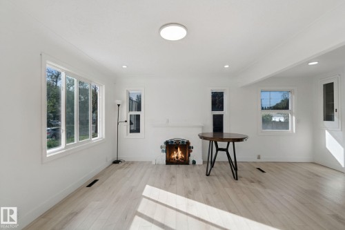 Light wood-finish flooring, recessed lighting, and a decorative fireplace with a tile surround - 11914 124 Street Nw, Edmonton, AB 