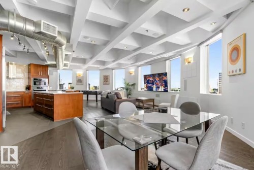 Open-concept living space with exposed ductwork, a coffered ceiling, and dark wood-finish flooring - #701 10105 109 St Nw, Edmonton, AB 