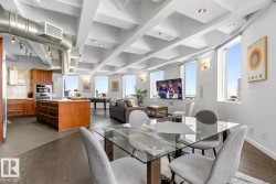 Open-concept living space with exposed ductwork, a coffered ceiling, and dark wood-finish flooring - 