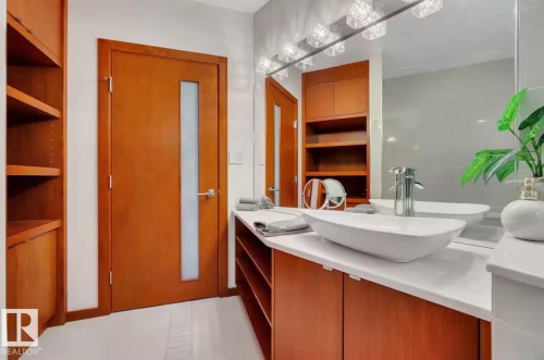 Modern bathroom featuring a vessel sink, white countertop, chrome faucet, and wood-finish cabinetry - #701 10105 109 St Nw, Edmonton, AB 