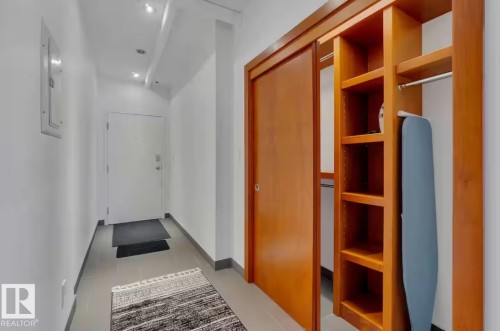 Entry foyer with recessed lighting, tile flooring, and a built-in closet featuring wood-finish shelving and a hanging rod - #701 10105 109 St Nw, Edmonton, AB 