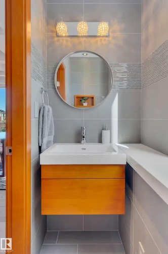 Wall-mounted vanity with a rectangular basin, chrome faucet, and wood-finish cabinetry - #701 10105 109 St Nw, Edmonton, AB 