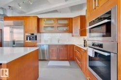 Kitchen featuring wood-finish cabinetry, stainless steel appliances, white countertops, and a built-in oven stack - 
