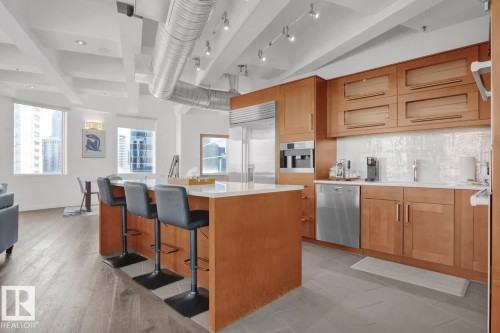 Gourmet kitchen with light wood cabinetry, a large center island, and stainless steel appliances - #701 10105 109 St Nw, Edmonton, AB 