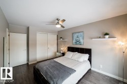 Wood-finish flooring, ceiling fan with integrated lighting, sliding closet doors, and wall-mounted shelving - 