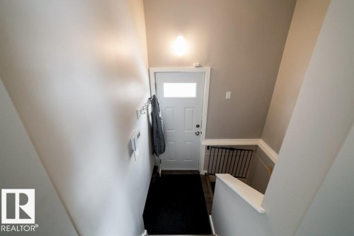 Entryway featuring a white paneled door with glass insert, wall-mounted light fixture, and contrasting wall colors - 12228 134 Street Nw, Edmonton, AB 
