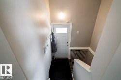Entryway featuring a white paneled door with glass insert, wall-mounted light fixture, and contrasting wall colors - 