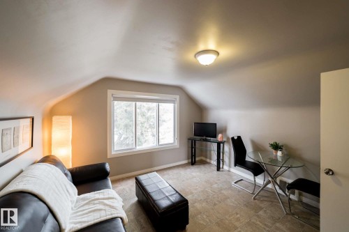 Sloped ceiling design, natural light from a multi-pane window, flush-mount ceiling fixture, and tile flooring - 12228 134 Street Nw, Edmonton, AB 