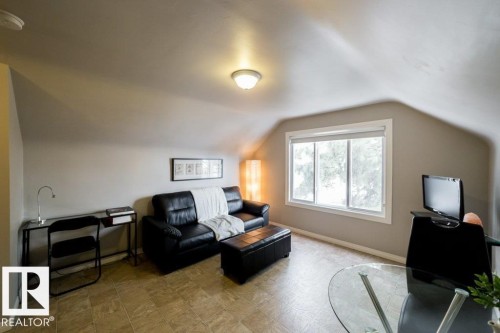 Angled ceilings, window with white trim, tiled flooring, built-in ceiling light fixture, and neutral wall tones - 12228 134 Street Nw, Edmonton, AB 