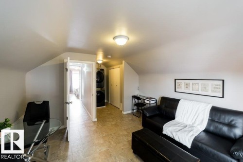 Sloped ceilings with flush mount lighting, durable tile flooring, and a built-in stacked washer and dryer unit - 12228 134 Street Nw, Edmonton, AB 