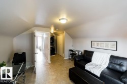 Sloped ceilings with flush mount lighting, durable tile flooring, and a built-in stacked washer and dryer unit - 