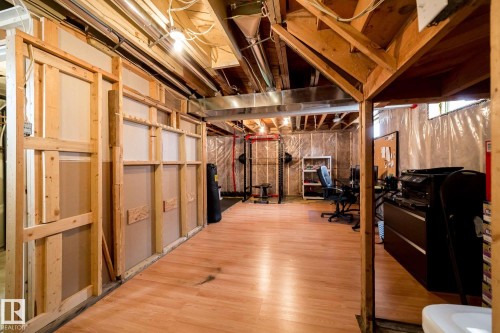 Unfinished lower level with exposed ceiling joists, wood-finish flooring, and framed wall sections - 12228 134 Street Nw, Edmonton, AB 