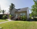 Exterior siding with decorative shingle accents, a dark shingle roof, and a front entry with handrails - 12228 134 Street Nw, Edmonton, AB 