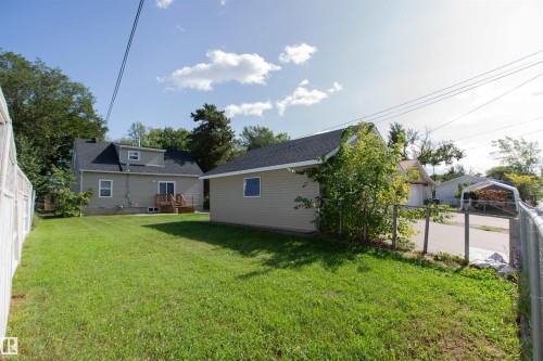 Expansive green lawn with a detached building, chain link fencing, a wooden deck, and mature trees - 12228 134 Street Nw, Edmonton, AB 