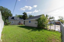 Expansive green lawn with a detached building, chain link fencing, a wooden deck, and mature trees - 