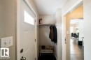 Convenient mudroom entry featuring white panel doors, built-in coat rod with hooks, and wood-finish flooring - 12228 134 Street Nw, Edmonton, AB 