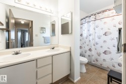 Bathroom featuring a dual-sink vanity with ample counter space, full-width mirror, and a built-in light fixture - 