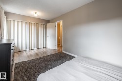 Bedroom featuring wood-finish flooring, neutral wall tones, and vertical window blinds - 