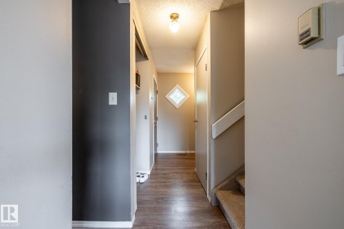 Hallway with wood-finish flooring and a diamond-shaped window - #20 3812 20 Av Nw, Edmonton, AB 