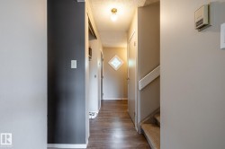 Hallway with wood-finish flooring and a diamond-shaped window - 