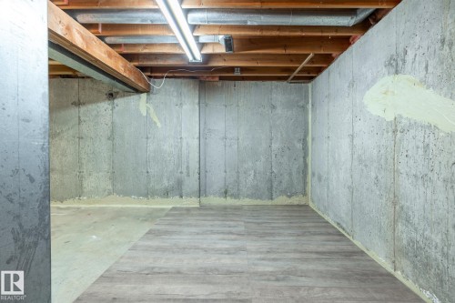Unfinished basement space featuring exposed concrete walls and ceiling joists - #20 3812 20 Av Nw, Edmonton, AB 