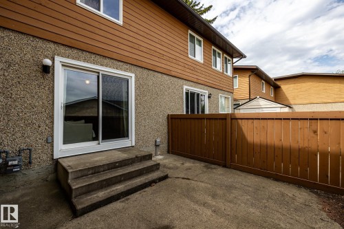 Exterior patio with concrete steps, a sliding glass door, and a brown wood fence - #20 3812 20 Av Nw, Edmonton, AB 