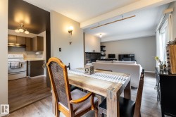 Open-concept living space featuring wood-finish flooring, a rustic wood dining table, and a kitchen with brown cabinetry and white appliances - 