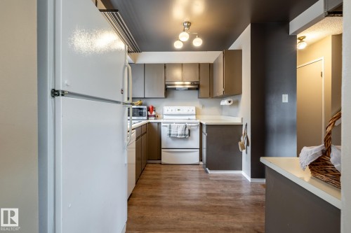 Kitchen featuring wood-finish flooring, white appliances, recessed lighting, and upper and lower cabinetry - #20 3812 20 Av Nw, Edmonton, AB 