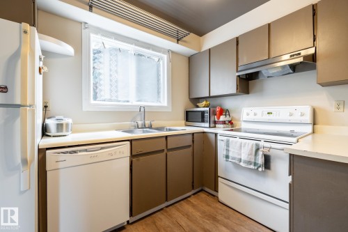 Kitchen featuring a double-basin stainless steel sink, white dishwasher, white electric range, and ample cabinetry - #20 3812 20 Av Nw, Edmonton, AB 