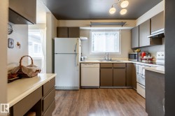 Kitchen featuring wood-finish flooring, white appliances, and a window above the sink - 