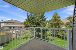Outdoor balcony featuring a textured floor, white metal railing, and a slatted ceiling - 