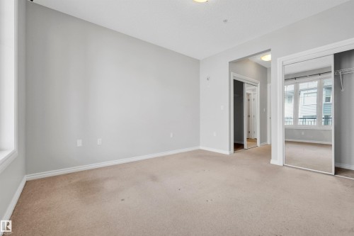 Recessed lighting, light-toned carpeting, and a mirrored closet door with built-in shelving - #215 9820 165 St Nw, Edmonton, AB 