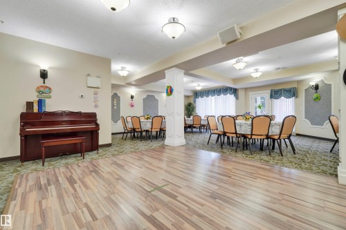 Expansive open space featuring diverse flooring, recessed lighting, decorative wall sconces, and architectural columns - #215 9820 165 St Nw, Edmonton, AB 