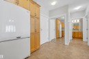 Hallway featuring tile flooring, built-in storage cabinetry, and mirrored closet doors - #215 9820 165 St Nw, Edmonton, AB 