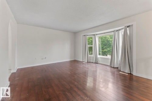 Expansive living space featuring wood-finish flooring and a multi-panel bay window - 4412 51 Avenue, Cold Lake, AB - Indoor Photo Showing Other Room
