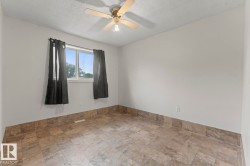 Interior space featuring light-toned walls, tile flooring, and a ceiling fan with integrated lighting - 