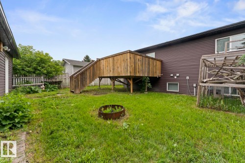 Spacious backyard featuring a raised wooden deck with stairs, a fire pit, and a partial wooden privacy fence - 4412 51 Avenue, Cold Lake, AB - Outdoor With Exterior