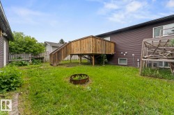 Spacious backyard featuring a raised wooden deck with stairs, a fire pit, and a partial wooden privacy fence - 
