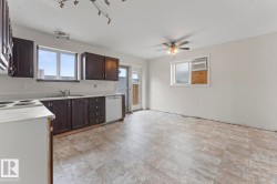 Kitchen space featuring dark wood-finish cabinetry, a white dishwasher, and a window above the sink - 