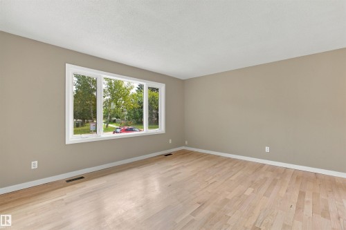 Light wood-finish flooring, neutral wall paint, and a large multi-pane window - 9908 99 Street, Morinville, AB 