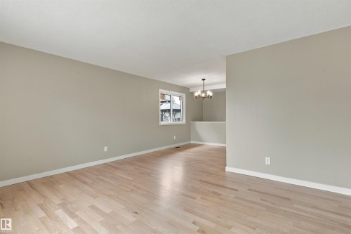 Light wood-finish flooring, neutral wall tones, and a visible window with white trim - 9908 99 Street, Morinville, AB 
