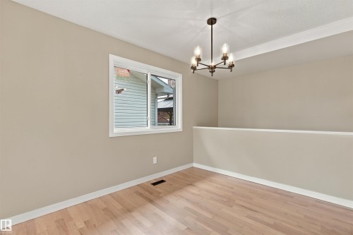 Wood-finish flooring, neutral wall tones, white trim, and a contemporary chandelier - 9908 99 Street, Morinville, AB 