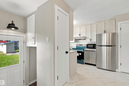 Kitchen featuring light-toned cabinetry, a speckled countertop, and white subway tile backsplash - 9908 99 Street, Morinville, AB 